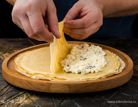 Разогреть блинную сковороду и, смазывая ее при помощи кулинарной кисточки оливковым маслом, испечь блины. На одну половинку каждого блина выложить немного творожной начинки, накрыть другой половинкой и сложить пополам, чтобы получились треугольники.