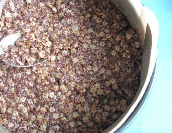 Форму смазать сливочным маслом, застелить пекарской бумагой (дно и борта). Положить в форму приготовленную массу. Утрамбовать влажной ложкой. 