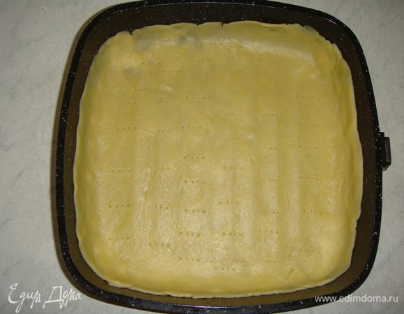 Тесто раскатать между двумя листами пергамента. Форму застелить пергаментом. Аккуратно перенести тесто в форму, сформировать бортики высотой ~4 см. Тесто наколоть вилкой и поставить в разогретую до 200°С духовку на 5 минут.