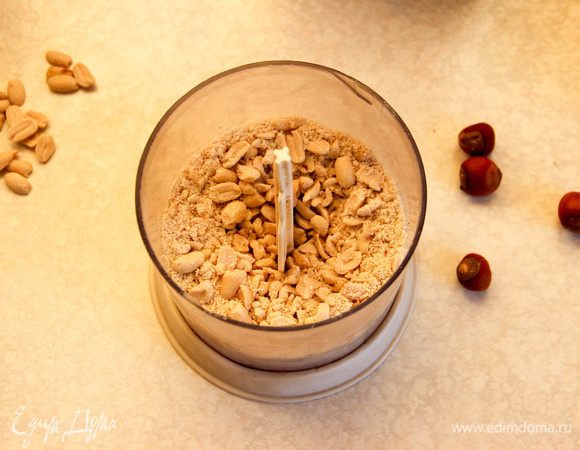 Первым делом приготовим ореховую нугу. Понадобится время, чтобы она застыла, прежде чем мы добавим ее в торт. Орехи (я использовала арахис, фундук, можно взять и грецкие) слегка поджарим на сковороде, затем измельчим в блендере. Сахар, мед и воду доводим на небольшом огне до кипения, варим 12 — 15 минут,  постоянно помешивая.