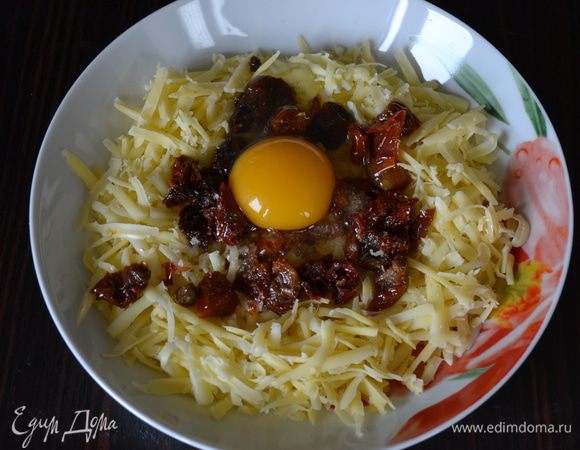 Тем временем для начинки натереть на крупной терке адыгейский сыр, нарезать на небольшие кусочки вяленые помидоры, чеснок пропустить через пресс и добавить яйцо. Перемешать.