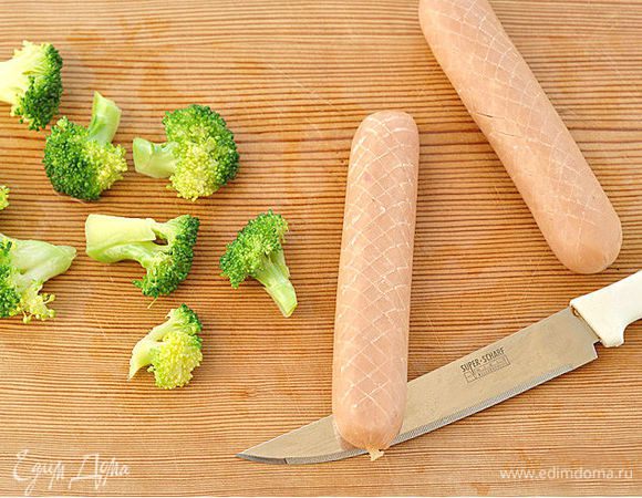 Разделить брокколи на части.
С помощью ножа сделать неглубокие надрезы в сосисках в виде ромбиков.