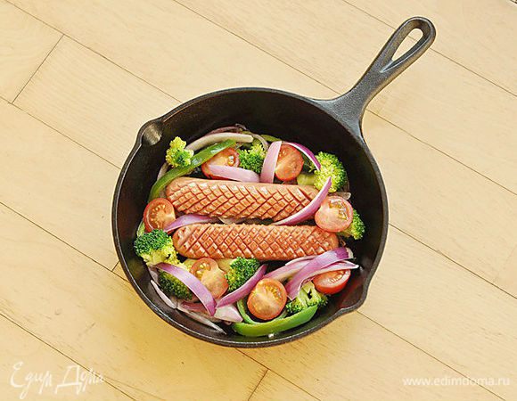 Положить на сковороду брокколи, помидоры и оставшийся лук.