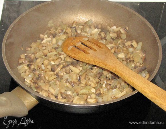 Пока подходит тесто, приготовим начинку. Лук измельчить, грибы мелко порезать. Разогреть в сковороде растительное масло и обжарить лук до мягкости. Затем добавить грибы и готовить, помешивая, до готовности. Переложить в миску, остудить.