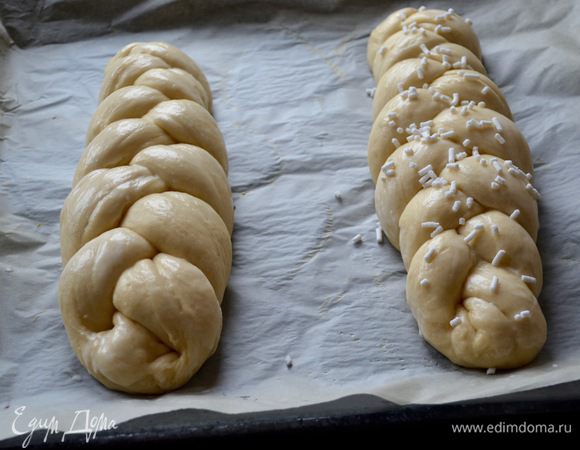 Выложить плетенки на застеленный пекарской бумагой противень, накрыть пленкой и оставить на расстойку еще на 40 минут. Духовку разогреть до 170°С. Плетенки смазать молоком или сливками (по желанию, можно присыпать гранулированным сахаром).