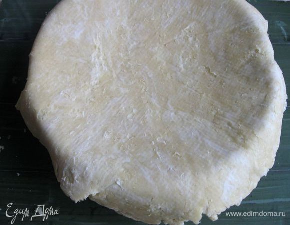 Положить тесто  в форму. Для этого я накрыла тесто перевернутой формой, под низ оставшейся бумаги подставила ладони, перевернула форму и тесто, сняла бумагу. Тесто переносится легко, если оно холодное. Некоторые для переноса теста в форму пользуются скалкой (кладут ее на тесто почти по центру с небольшим смещением, чтобы полуокружности теста в дальнейшем совместились, перекидывают аккуратно на скалку одну из частей, переносят к форме, кладут в форму, расправляя края).
