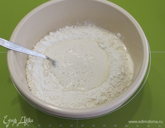 В центре сделайте углубление и влейте дрожжевую смесь. Перемешайте смесь вилочкой, постепенно вовлекая в процесс муку от центра к периферии.