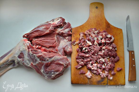 Откройте баранью ногу, подровняйте края и нарежьте на мелкие кусочки обрезки мяса.