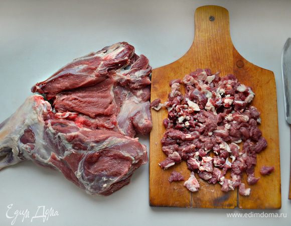 Откройте баранью ногу, подровняйте края и нарежьте на мелкие кусочки обрезки мяса.