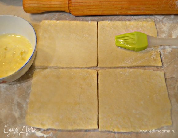 После охлаждения снова месите тесто еще несколько минут и оставьте его еще на полчаса, прежде чем раскатать в тонкий пласт. После нарежьте пласт на квадраты со стороной 10 см и смажьте поверхность взбитым яйцом.