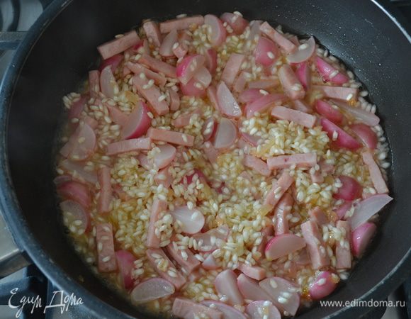 Через 2 — 3 минуты увеличить огонь и влить белое сухое вино. Дать вину выпариться. Огонь уменьшить до среднего. Продолжать готовить ризотто, подливая горячий бульон по мере того, как он будет впитываться, и время от времени помешивая, примерно 16 — 18 минут.