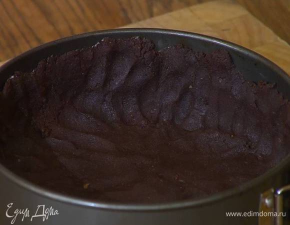 Разъемную форму для выпечки смазать оставшимся сливочным маслом и равномерно распределить тесто по дну и бортам. Часто наколоть тесто вилкой и отправить в разогретую духовку на 15 минут.