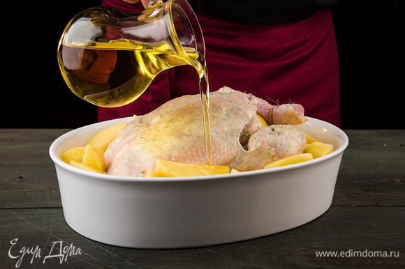 Картофель почистить, нарезать крупно, сбрызнуть оставшимся растительным маслом, посолить, разложить вокруг курицы. Запекать в разогретой духовке около часа.