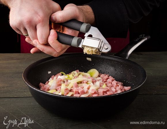 Для начинки: ветчину мелко нарезать, лук порей нарезать кольцами, зубчик чеснока натереть на мелкой терке или раздавить прессом. Обжарить все вместе в сотейнике 4 — 5 минут.