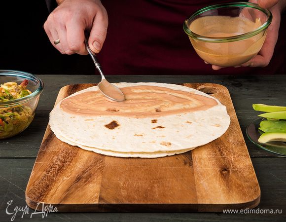 Тортильи слегка прогреть на сковороде. Теплые лепешки смазать соусом.