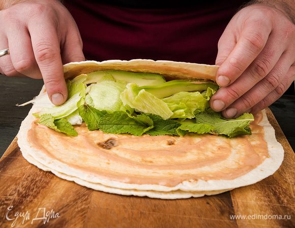 На один край выложить креветки с овощами, авокадо, листья салата и мяты и свернуть рулетом.