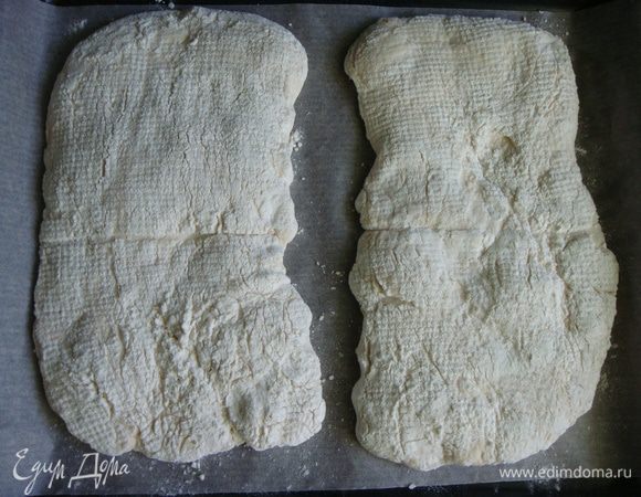 Духовку разогреть до 200°С вместе с противнем. Застелить его пергаментом и присыпать мукой. Аккуратно перенести чиабатту на противень, смахнуть излишки муки кисточкой. Выпекать хлебушек 30 минут, до румяной корочки.