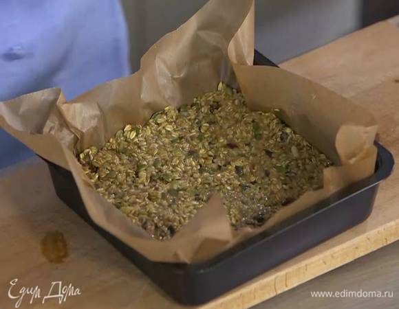 Небольшой противень с высокими бортами выстелить бумагой для выпечки, выложить овсяную массу и разровнять ее, слегка утрамбовав, так чтобы получился корж толщиной 1‒2 см.