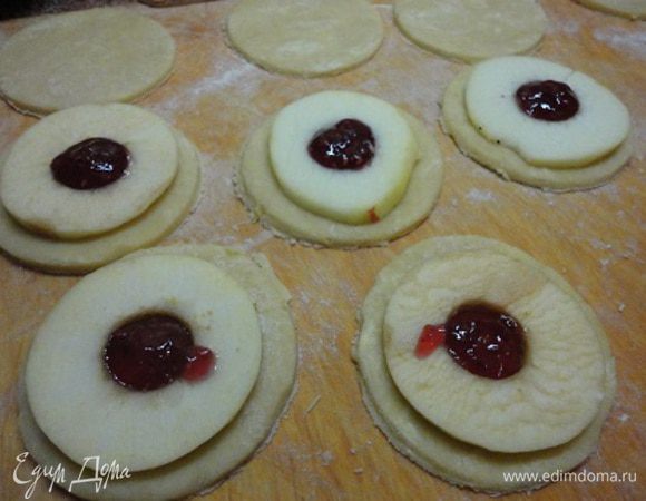 Тонко раскатать тесто (3 — 5 мм), вырезать парное число кружков нужного диаметра. На половину кружков уложить кольца яблок, в центр — немного джема или мармелада. У меня малиновый джем. В опциях его не было. Этот джем выбрала случайно, но оказалось просто превосходное сочетание.