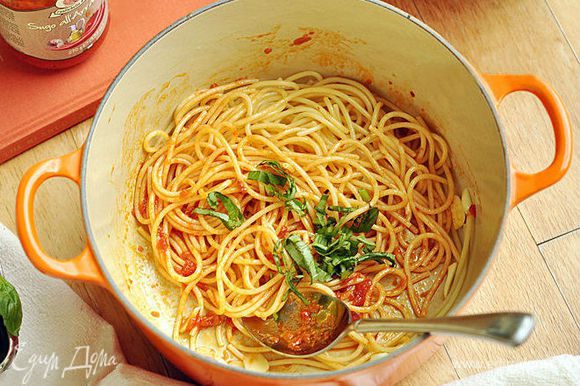 Положить в кастрюлю спагетти, добавить томатную пасту и перемешать. Добавить нарезанные листья базилика.