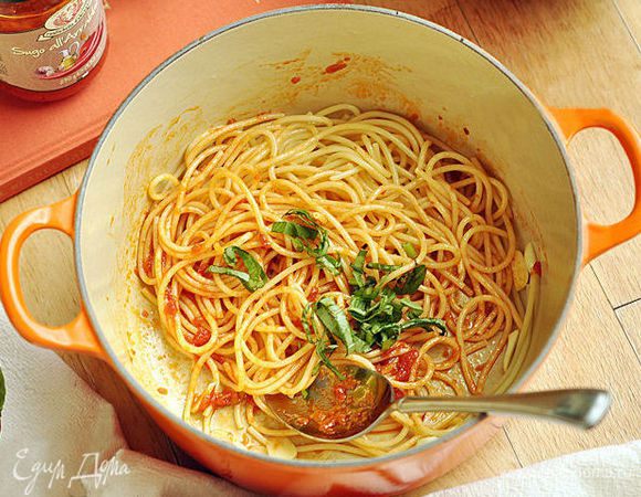 Положить в кастрюлю спагетти, добавить томатную пасту и перемешать. Добавить нарезанные листья базилика.