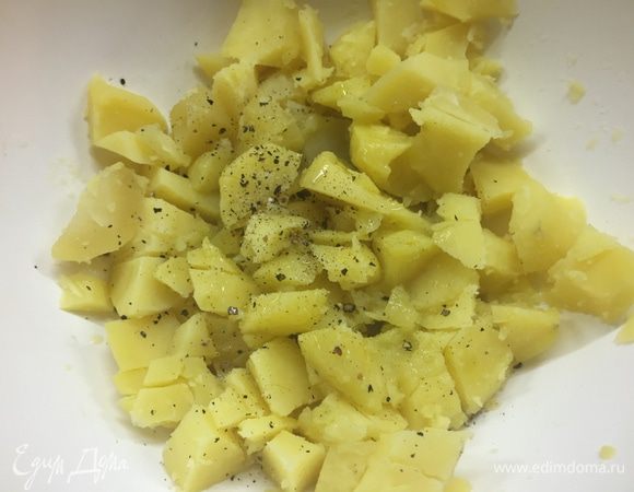 Прямо в миске грубо режем ее ножом, стараясь не обжечься. Я просто кромсаю ее, даже не дотрагиваясь руками. Этому салату это нисколько не вредит. Делаем все быстро, потому что чем горячее картошка, тем лучше она вберет в себя все вкусы. Итак: порезали и тут же вливаем оливковое масло, сок лимона, щедро перчим, немного солим с расчетом на то, что в салате будут соленые огурцы. 