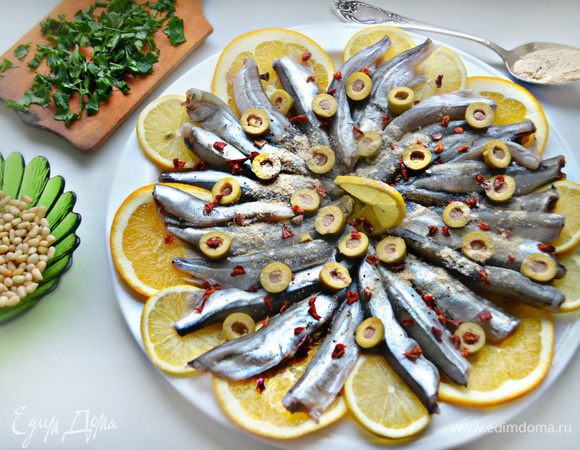 Блюдо для запекания смажьте оливковым маслом, уложите по кругу кружки апельсина и лимона, рыбку, слегка присолите. Порежьте кружочками оливки и распределите поверх рыбы, посыпьте хлопьями сладкой паприки, кедровыми орешками (итал. — «пиноли»), молотыми сухарями, полейте вином, сбрызните соком апельсина и лимона (выделившимся при нарезании), оливковым маслом и поставьте в разогретую до 180°С духовку на 15 минут.