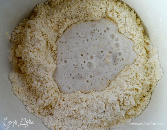 По центру массы сделаем небольшое углубление. Сюда выливаем опару и замешиваем тесто.