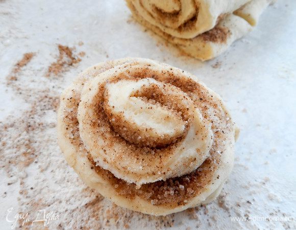 Переворачиваем каждый кусочек и раскрываем слои, как лепестки цветка. Получаются вот такие розочки. Выкладываем булочки на противень, смазанный маслом. Ставим в разогретую духовку. Выпекаем 20—25 минут при температуре 180°С. 