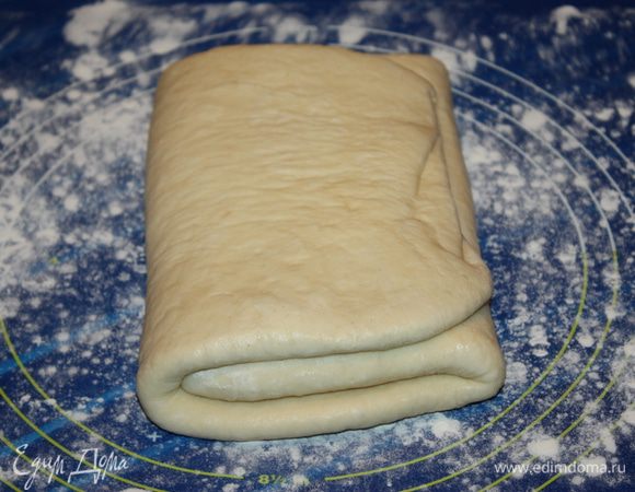 Прослаивание теста.
Масло (400 г) для прослойки теста делим на 7 равных частей. Рабочую поверхность слегка подпыляем мукой и выкладываем на него тесто. Раскатываем его в прямоугольный пласт. Смазываем 2/3 поверхности теста одной частью масла. Складываем тесто в три раза. Сначала заворачиваем край не промазанного теста, а на него кладем промазанный край. 
