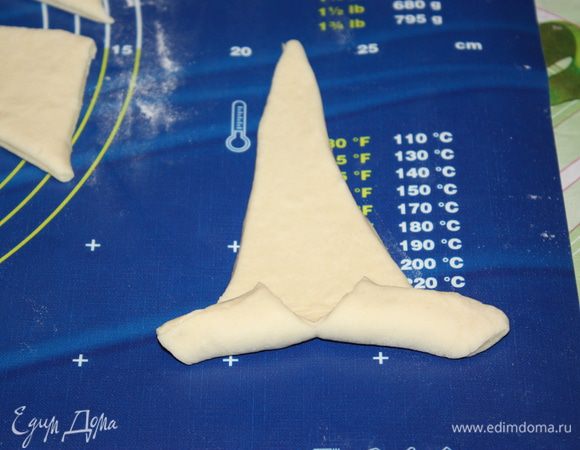 Начинаем скручивать тесто в круассаны. Только не прижимайте тесто. Его просто нужно свернуть, а не деформировать. Для этого не забывайте припылять рабочую поверхность мукой, чтобы тесто не приклеивалось. 