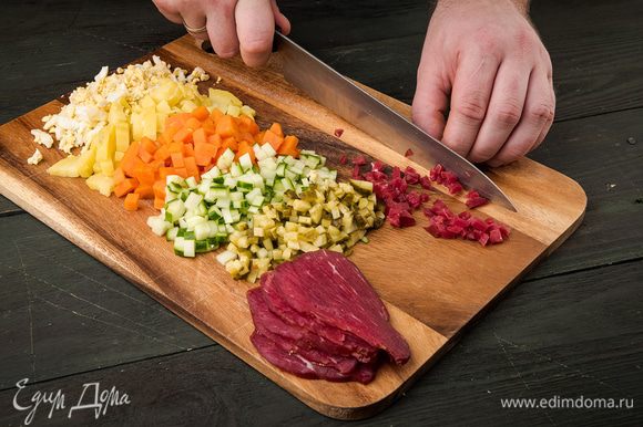 Морковь, картофель, яйца отварить и нарезать кубиками. Так же нарезать свежие и соленые огурцы. Копченую говядину нарезать кубиками побольше.