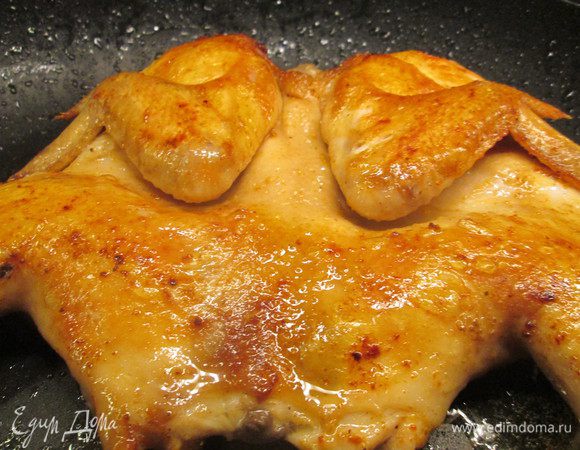 Посолить внешнюю часть курицы, нагреть масло в сковороде. Курицу поместить на сковороду кожей вниз, прижать руками. Жарить минуты 4 и посолить верхнюю часть курицы. 
Далее смешиваем оливковое масло с паприкой, специями и смазываем смесью курицу. 
Переворачиваем на другую сторону, снова смазываем маслом со специями и жарим, уменьшив огонь, чтобы курица не пригорела. Повторяем это неоднократно.