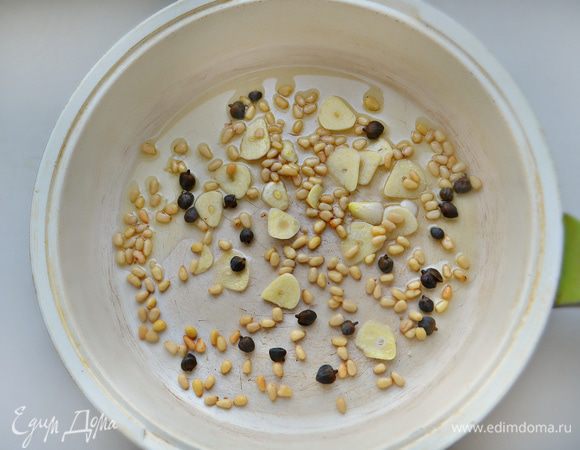 В глубокой сковороде разогрейте оливковое масло. Добавьте нарезанный пластинами чеснок, орешки и каперсы. Обжаривайте, помешивая, 2 — 3 минуты.