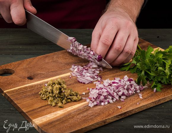 Багет нарезать ломтиками толщиной 2 см. Лук нарезать кубиками, каперсы нарезать мелко, петрушку измельчить.
