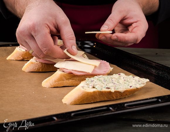 На каждый кусочек багета выложить топпинг, сверху накрыть его ветчиной и слайсом сыра. Поставить в духовку на 5 минут при 180°С.