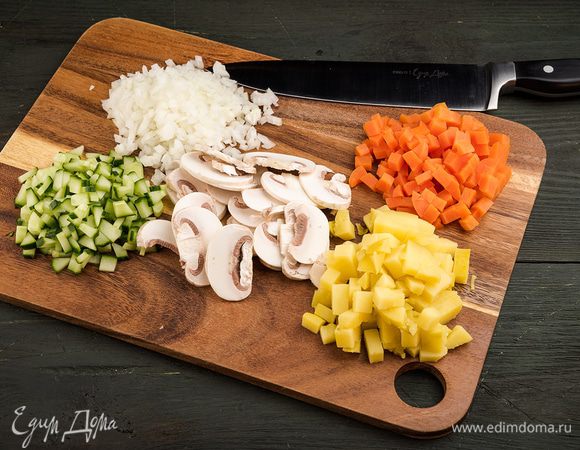 Отвариваем картофель и морковь. Нарезаем кубиками картофель, морковь, лук, огурцы и грибы. Измельчаем петрушку. 
