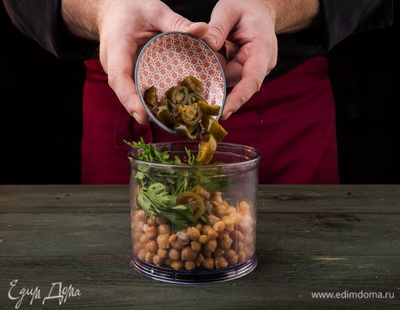 Нут отварить до готовности. Сложить нут, перец халапеньо и петрушку в блендер и измельчить до однородной массы.
