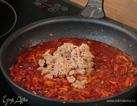 Через указанное время добавить в томатный соус кусочки тунца из банки (предварительно слив жидкость) и нарезанную зелень петрушки. Проверить соус на соль. Потушить все вместе еще минут 5 и снять с огня.
