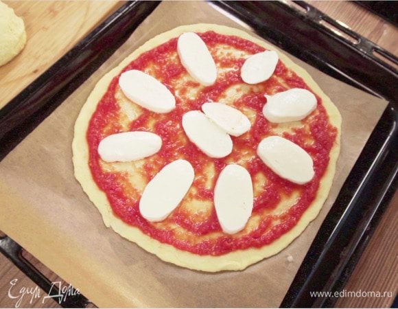 Выложить на смазанный оливковым маслом противень. Выложить приготовленное из свежих помидоров томатное пюре на тесто, сверху положить нарезанный кружочками свежий сыр моцарелла (или натереть моцареллу для пиццы на терке).
