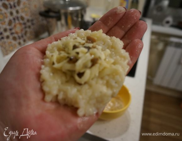 Смачиваем руки холодной водой и делаем из рисовой смеси круглые лепешки. В середину кладем начинку и аккуратно сворачиваем в шарик. Шарик должен быть небольшим и плотным.