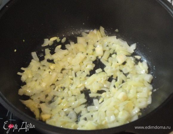 В чугунной сковороде или казане разогрейте растительное и сливочное масло, и прожарьте до мягкости мелко нарезанный лук и чеснок.
