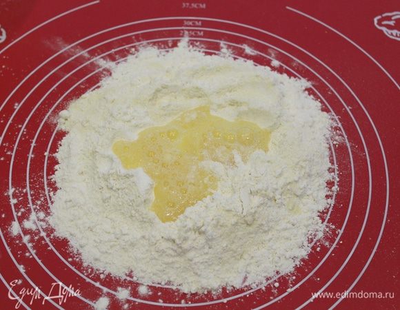 Сделайте углубление в муке, вылейте в серединку слегка взбитые с солью яйца.