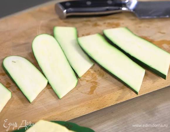 Цукини вместе с кожурой нарезать вдоль тонкими пластинками, затем разрезать их пополам, смазать оливковым маслом и обжаривать на сковороде-гриль с обеих сторон до появления золотистых полосок.