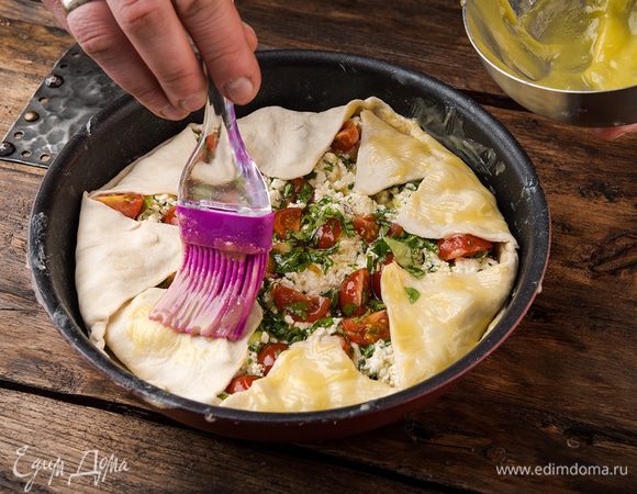 Промазать сливочным маслом свисающее тесто и загнуть его внутрь по краям тарта так, чтобы начинка в центре осталась открытой. Выпекать в разогретой духовке 15 минут.
