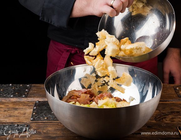 Листья фриссе отправить в глубокую салатницу. Чайной ложкой сформировать из мякоти авокадо небольшие шарики, уложить их на салат, сверху разложить крутоны и бекон.