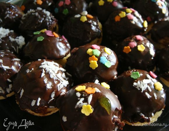 Пока шоколад не застыл, украсить шарики кондитерской посыпкой. После того, как шоколад застынет, переложить кейк-боллы в бумажные капсулы. Блюдо для детского праздника готово!