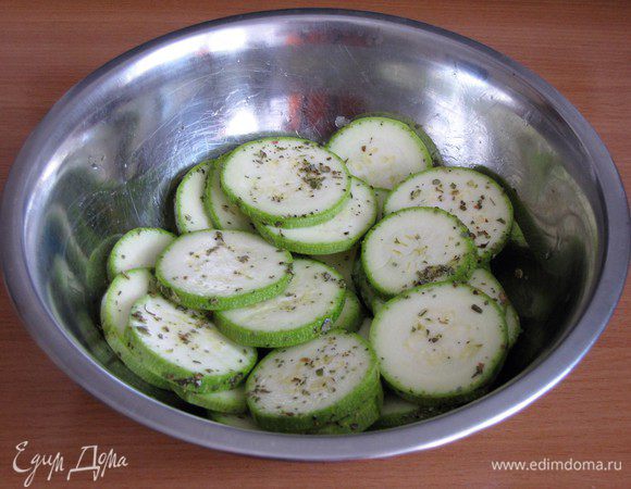 Небольшой молодой цукини или кабачок нарезать тонкими кружочками толщиной 5 мм, выложить в миску, полить оливковым маслом, посыпать перцем и орегано. Перемешать, чтобы специи равномерно распределились.