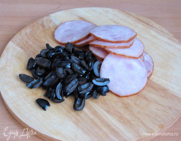 Оливки разрезать пополам, ветчину нарезать тонкими ломтиками.