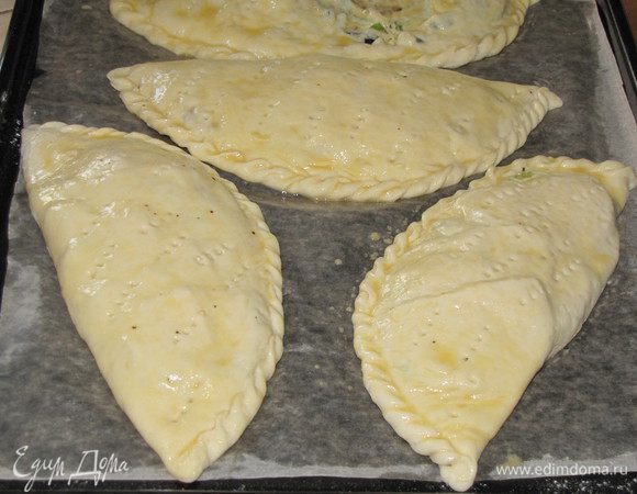 Выложить кальцоне на противень, застеленный пекарской бумагой. Бумагу можно смазать маслом. Оставить на 15 минут для расстойки. Слегка взбить яйцо и смазать кальцоне с помощью кулинарной кисти. Сделать несколько проколов вилкой для выхода пара. Поставить в разогретую до 180°С духовку на 15 — 20 минут.